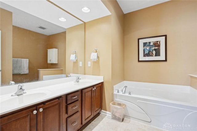 bathroom with recessed lighting, double vanity, a garden tub, and a sink