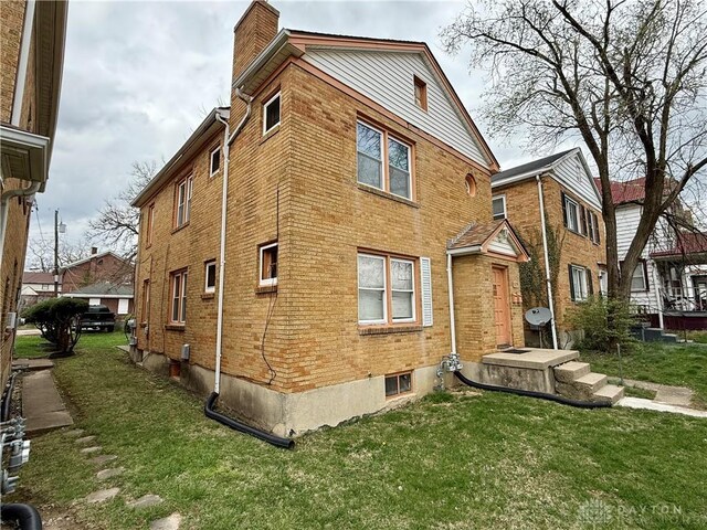 1029 Cumberland Ave, Dayton, OH 45406 - view of side of home with a chimney, brick siding, and a yard