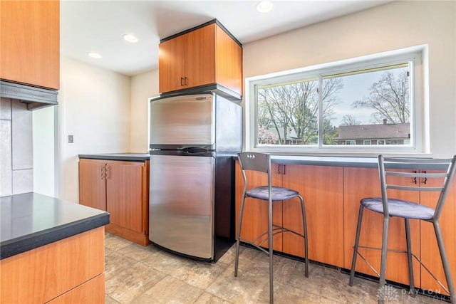 645 Brookfield Rd, Dayton, OH 45429 - kitchen featuring freestanding refrigerator, a kitchen breakfast bar, dark countertops, recessed lighting, and brown cabinets