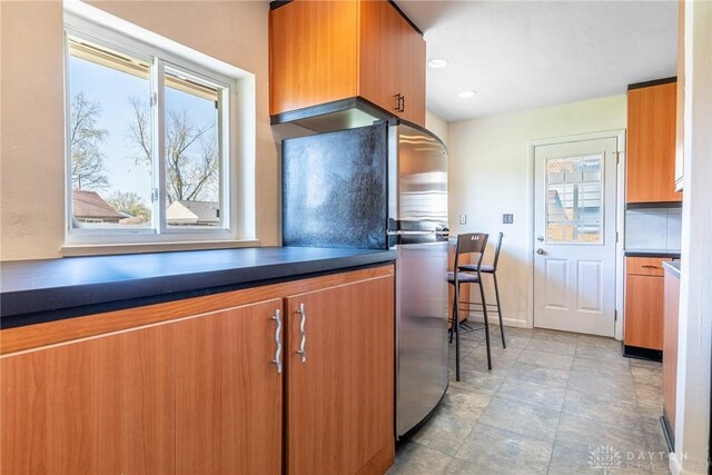 645 Brookfield Rd, Dayton, OH 45429 - kitchen with freestanding refrigerator, dark countertops, brown cabinetry, and stone finish flooring