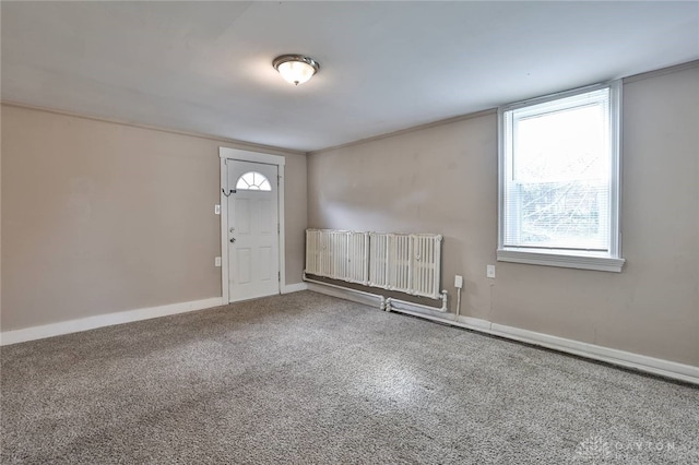 carpeted entryway with radiator heating unit and baseboards