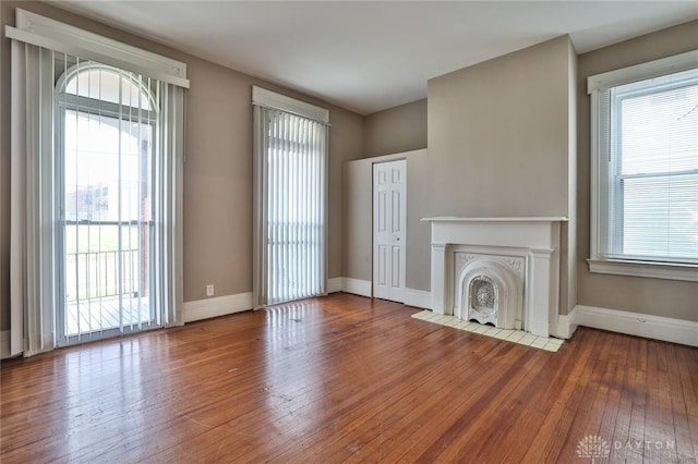 unfurnished living room with a fireplace with flush hearth, baseboards, and hardwood / wood-style flooring