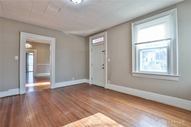 foyer entrance with wood-type flooring, a notable chandelier, baseboards, and a healthy amount of sunlight