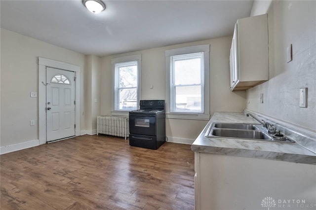 kitchen featuring a sink, light countertops, radiator, dark wood-type flooring, and black electric range
