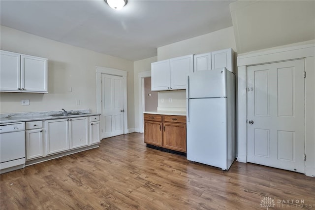 kitchen featuring white appliances, light wood-style flooring, light countertops, white cabinetry, and a sink