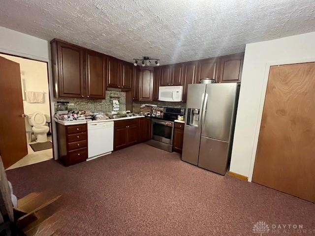 kitchen featuring tasteful backsplash, light countertops, appliances with stainless steel finishes, and a textured ceiling
