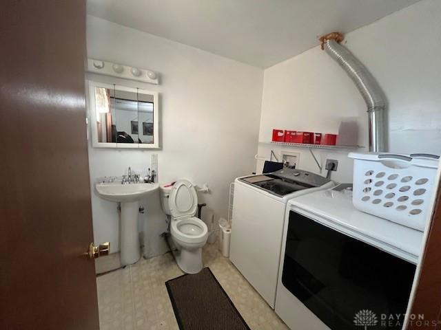bathroom with a sink, tile patterned floors, washer and clothes dryer, and toilet