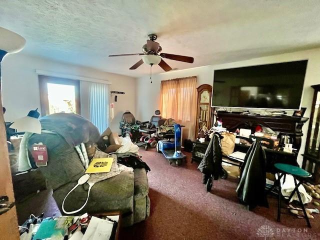 living area featuring a textured ceiling, a ceiling fan, and carpet floors