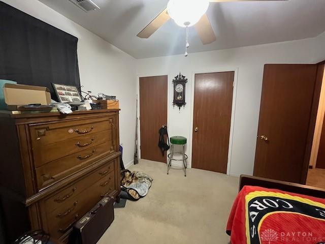 bedroom featuring visible vents, ceiling fan, and light carpet