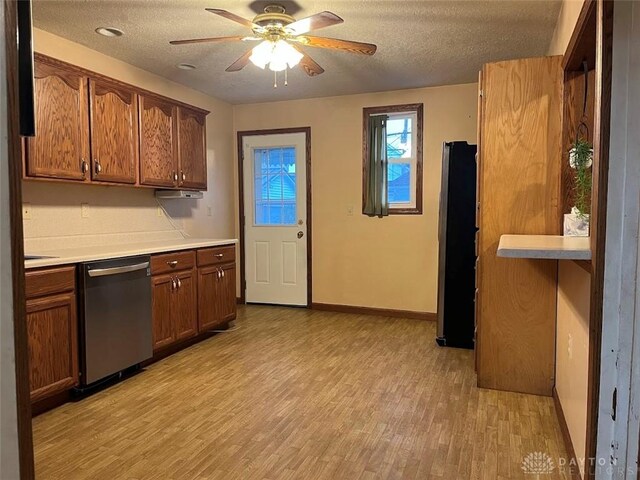 kitchen featuring a textured ceiling, stainless steel dishwasher, light wood finished floors, and a ceiling fan