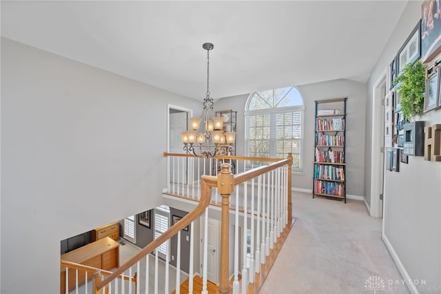 hall with an inviting chandelier, baseboards, an upstairs landing, and carpet floors
