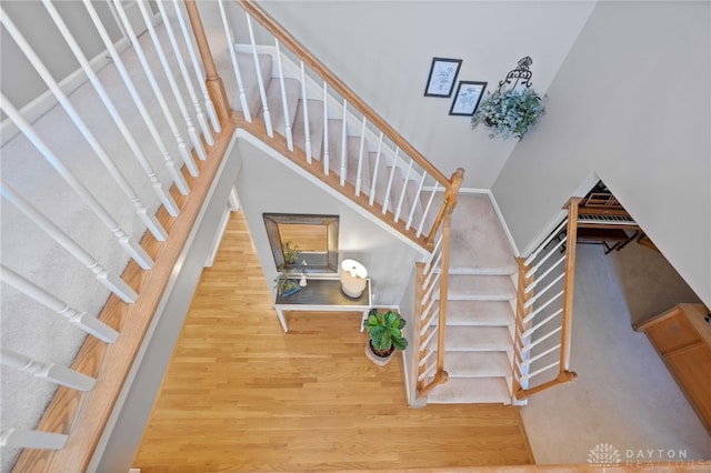 stairway featuring wood finished floors and a towering ceiling