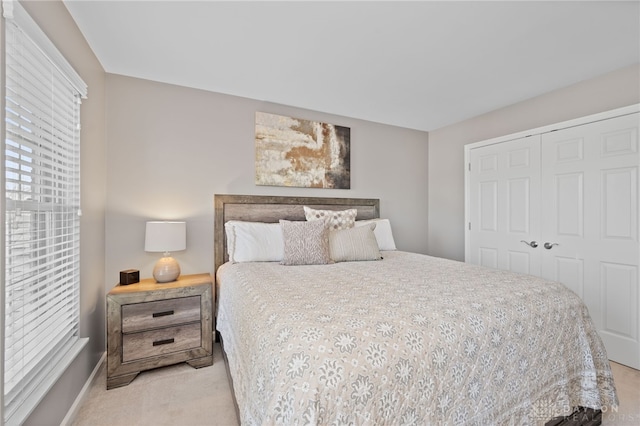 bedroom featuring a closet, baseboards, and light colored carpet