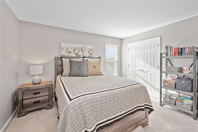 bedroom with light carpet, a closet, and baseboards