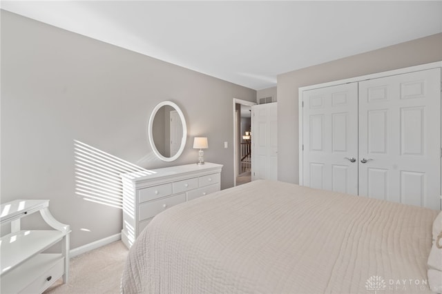 bedroom with light carpet, visible vents, a closet, and baseboards