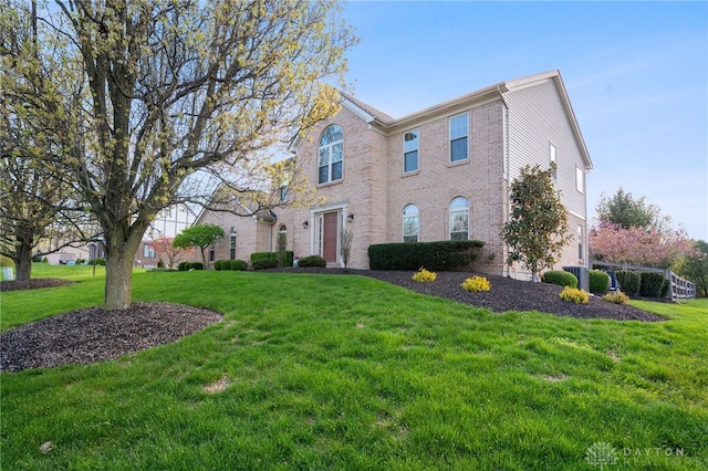 colonial inspired home with a front yard and brick siding
