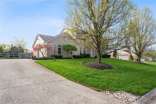 view of front of property featuring driveway, fence, a front lawn, and brick siding