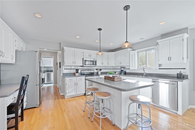 kitchen featuring a kitchen island, white cabinetry, a sink, and appliances with stainless steel finishes
