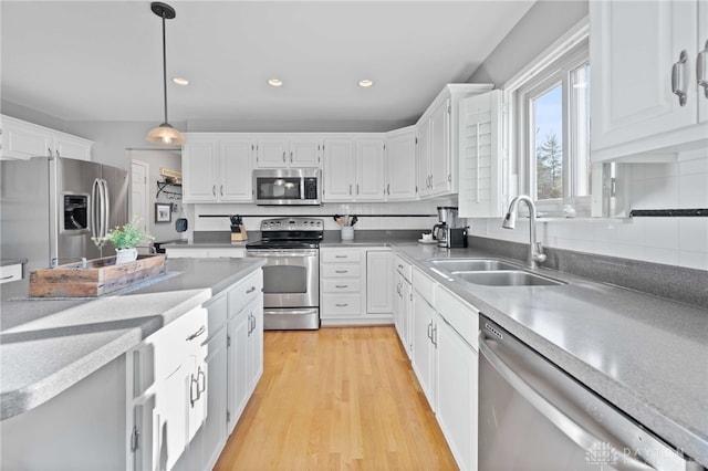 kitchen with decorative light fixtures, white cabinetry, a sink, and appliances with stainless steel finishes