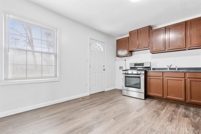kitchen featuring brown cabinets, baseboards, light wood finished floors, and gas range