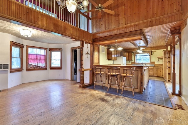 kitchen featuring a peninsula, freestanding refrigerator, wood finished floors, and visible vents