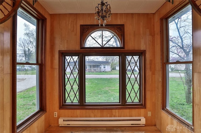 doorway to outside with a baseboard heating unit, a chandelier, and wooden walls