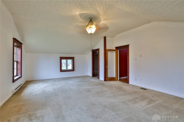 unfurnished room featuring a baseboard heating unit, lofted ceiling, visible vents, and carpet floors