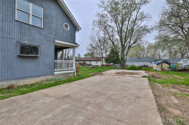 view of side of property featuring concrete driveway and a porch