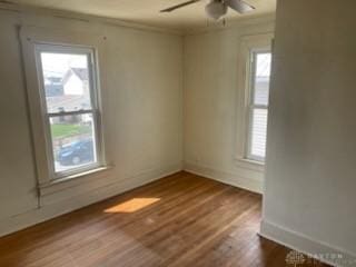 empty room featuring baseboards, wood finished floors, crown molding, and ceiling fan