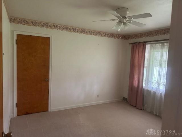 empty room featuring visible vents, ceiling fan, baseboards, and light carpet