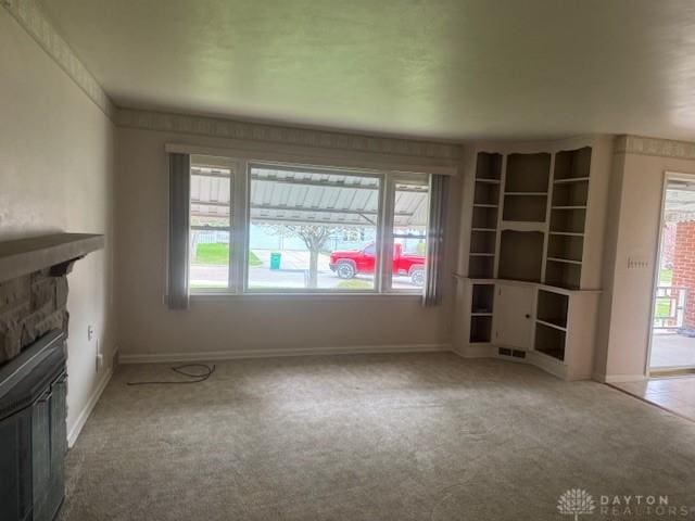 unfurnished living room with carpet floors, plenty of natural light, and a fireplace