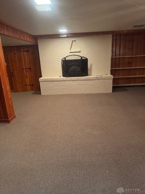 finished below grade area with carpet floors, a brick fireplace, and wooden walls