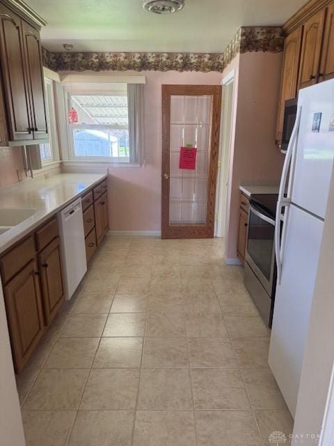 kitchen with baseboards, white appliances, and light countertops