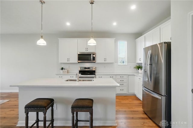 1110 Billingsley Dr, Batavia, OH 45103 - kitchen featuring appliances with stainless steel finishes, a breakfast bar, a kitchen island with sink, decorative backsplash, and a sink