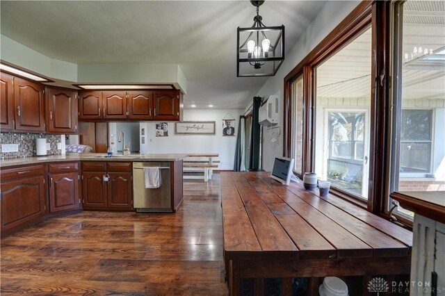 kitchen featuring stainless steel dishwasher, an inviting chandelier, a peninsula, a wall unit AC, and a sink