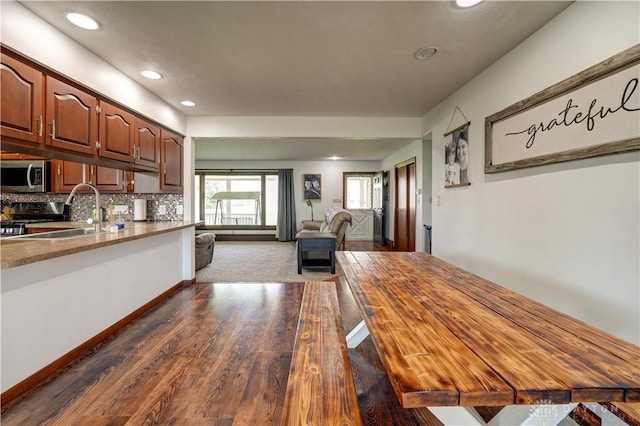 kitchen with a sink, open floor plan, dark wood-style flooring, appliances with stainless steel finishes, and recessed lighting