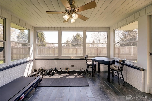 workout area with brick wall, dark wood-style flooring, wooden ceiling, and ceiling fan
