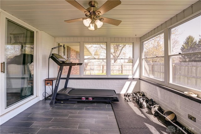 workout room featuring brick wall and a ceiling fan