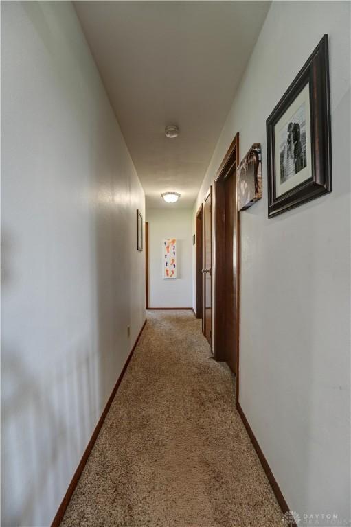 hallway with light colored carpet and baseboards