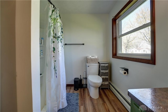 full bath featuring a shower with shower curtain, baseboards, toilet, a baseboard radiator, and wood finished floors