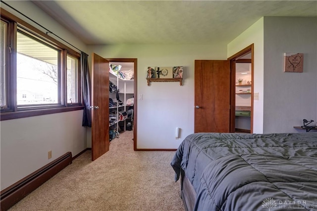 bedroom with a closet, baseboards, a baseboard radiator, carpet, and a walk in closet