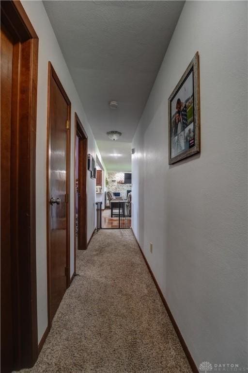 hall featuring baseboards and light colored carpet