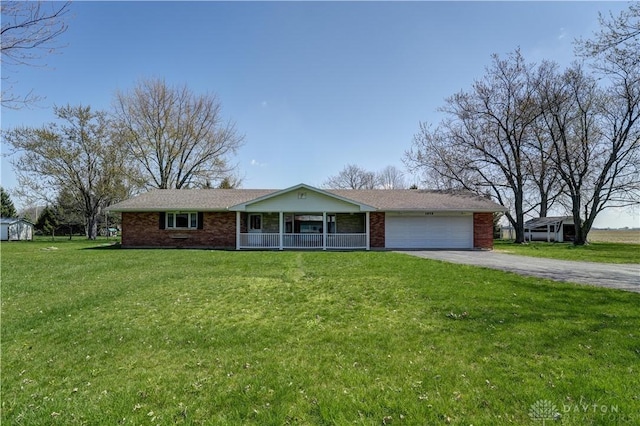 ranch-style home with a front yard, an attached garage, covered porch, aphalt driveway, and brick siding