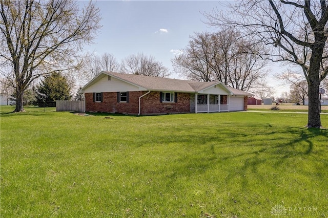 back of property featuring a garage, a yard, brick siding, and fence