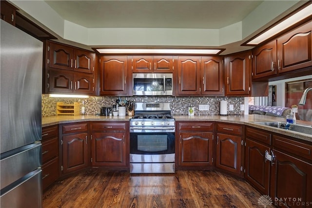 kitchen with decorative backsplash, a sink, dark wood-style floors, and stainless steel appliances