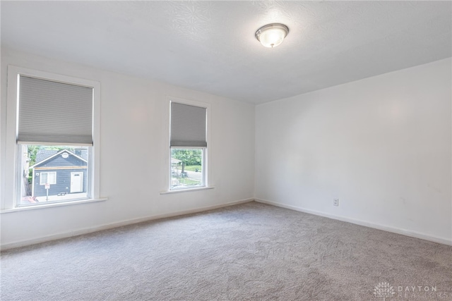 unfurnished room featuring carpet flooring, baseboards, and a healthy amount of sunlight