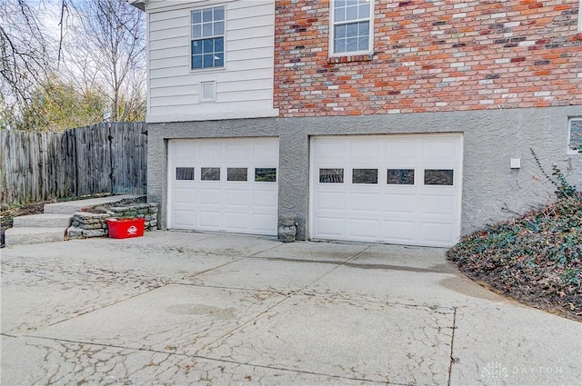 garage with fence and concrete driveway