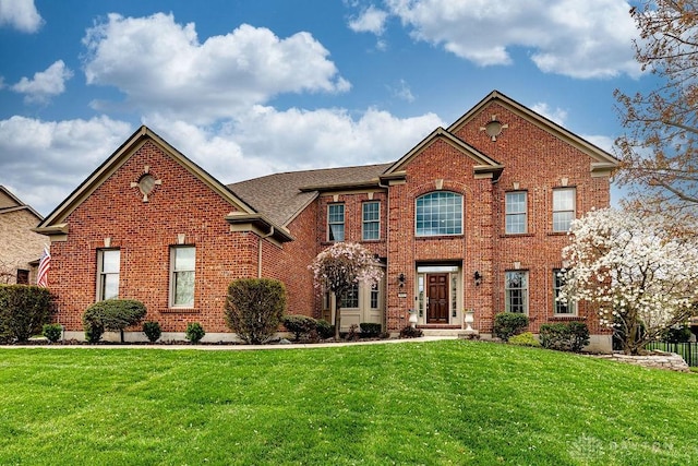 colonial house with a front yard and brick siding