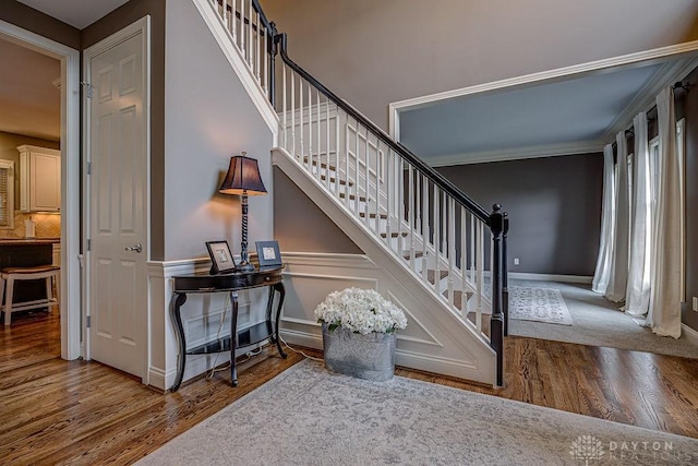 staircase with crown molding and wood finished floors