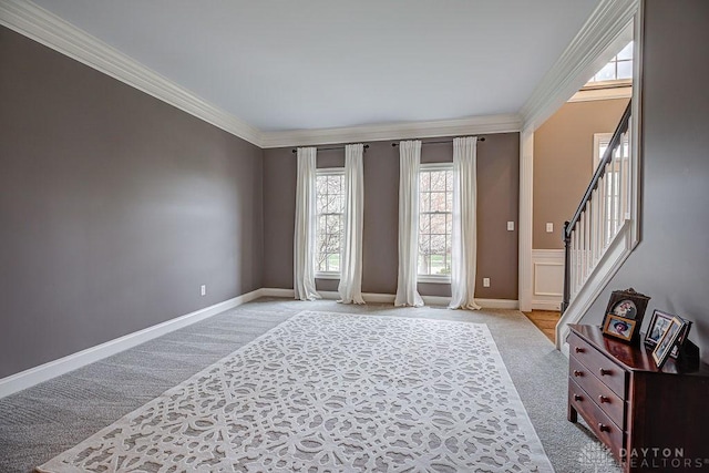 interior space with light colored carpet, baseboards, ornamental molding, and stairway